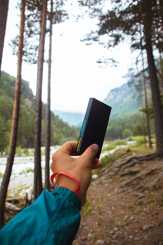 Power Bank NITECORE в руках человека, в лесу.